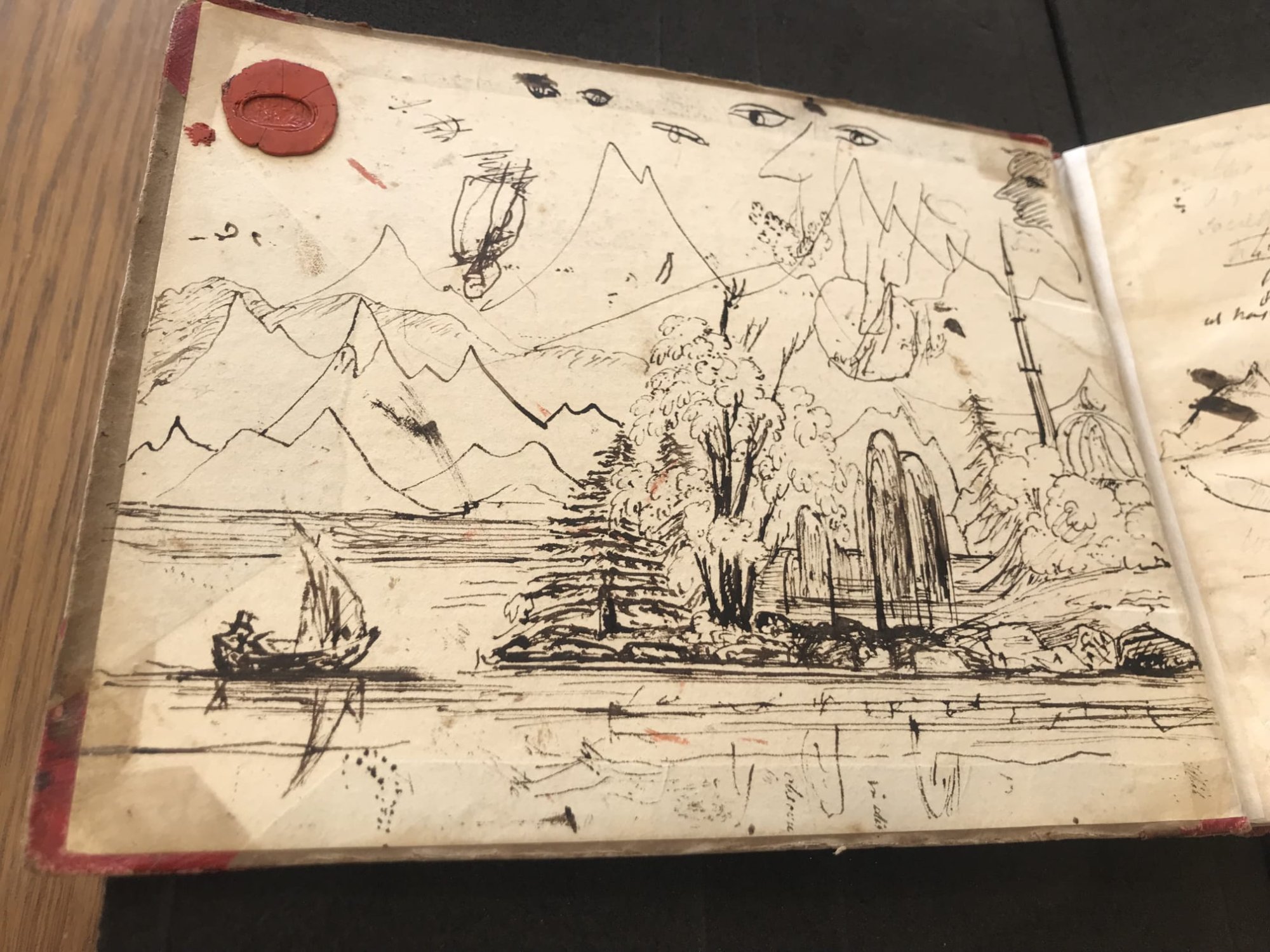 Percy Shelley's notebook cover showing an elaborate alpine lake scene in ink — mountains, pine trees, a sailing boat — with the original red wax seal still intact in the top corner